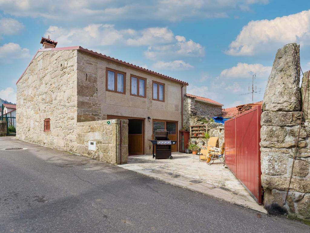 uma casa de pedra com uma porta vermelha numa rua em Cantinho do Lúcio em Melgaço