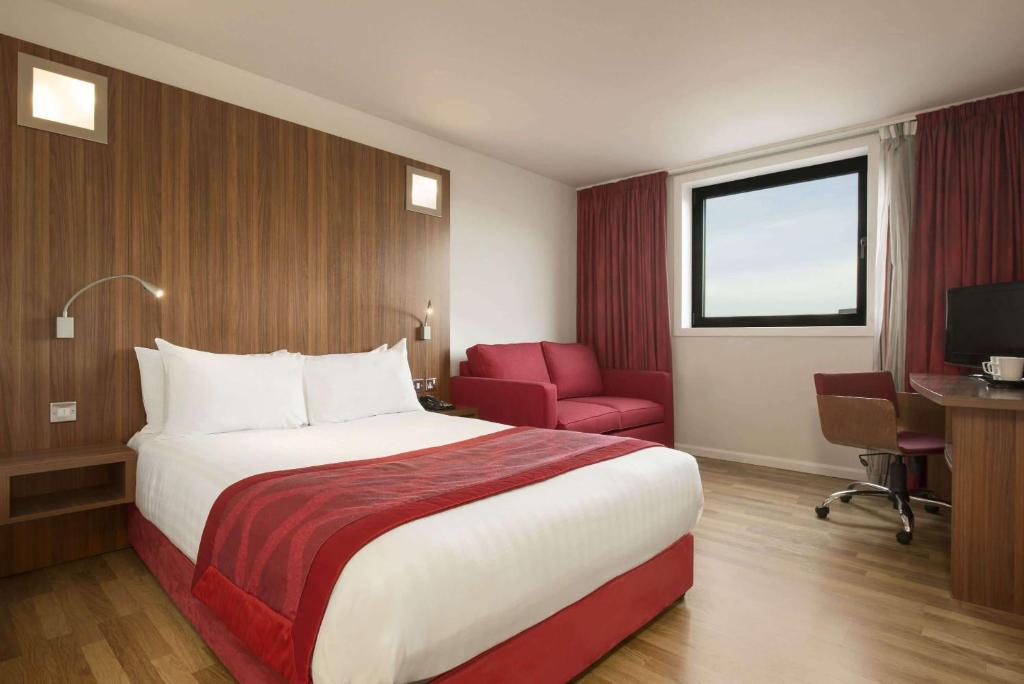 a hotel room with a large bed and a red chair at Ramada Encore Newcastle-Gateshead in Newcastle upon Tyne
