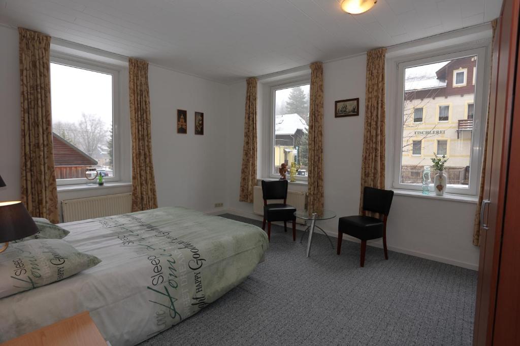 a bedroom with a bed and two chairs and windows at Haus Stefanie Elvire in Kurort Altenberg