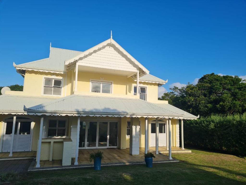 une maison jaune avec une terrasse couverte dans l'établissement Caribbeans Estates 76/34, à Port Edward