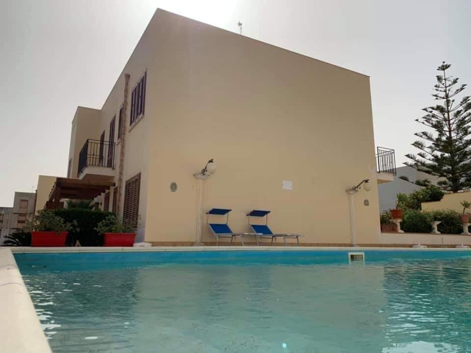 a swimming pool with two blue chairs next to a building at Casa Vacanza Blue Sea in San Vito lo Capo