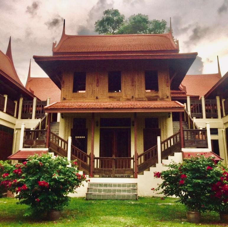 ein großes Holzgebäude mit einem Balkon und Blumen in der Unterkunft Luang Chumni Village in Phra Nakhon Si Ayutthaya