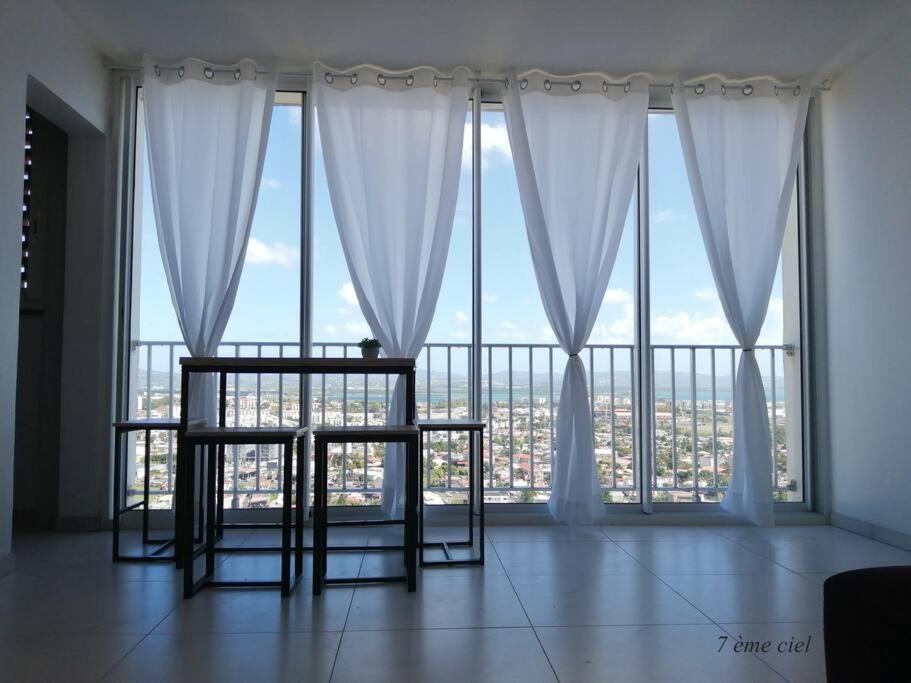 a room with a large window with white curtains at Bienvenue au 7ème ciel dans le spacieux T3 ! in Fort-de-France