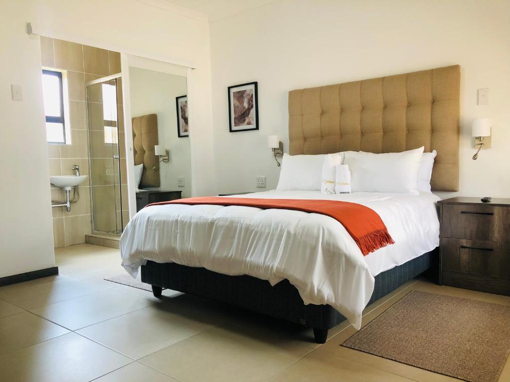 a bedroom with a large bed and a bathroom at Tranquility Guesthouse in Standerton