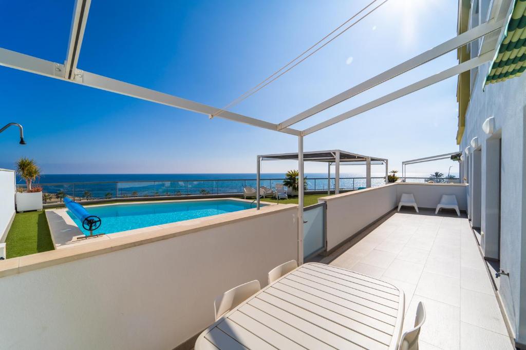 a balcony with a table and a swimming pool at Vistamar Luxury Apartments By DLV -Adults Only- in Villajoyosa