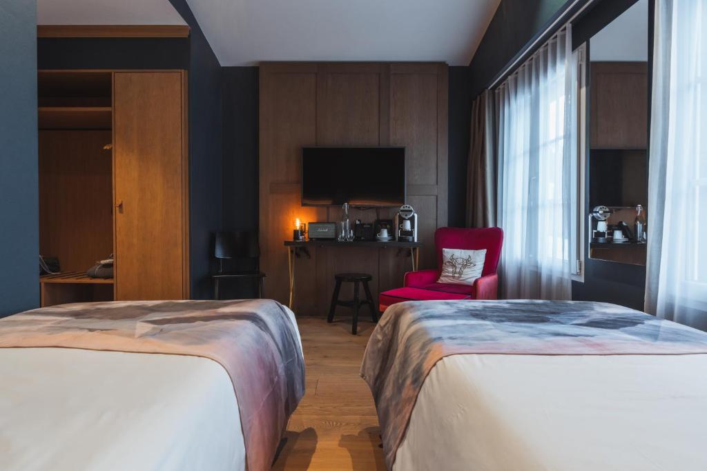 a hotel room with two beds and a red chair at Boutique Hotel Glacier in Grindelwald