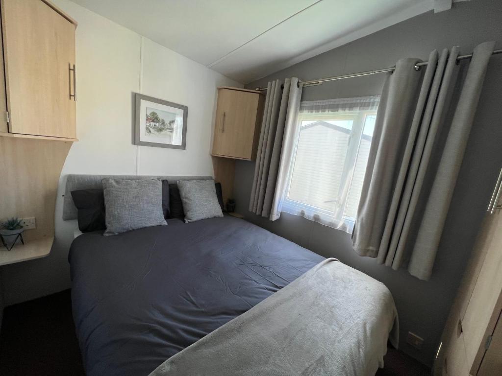 a small bedroom with a bed and a window at Forest & beach access Naish park in New Milton