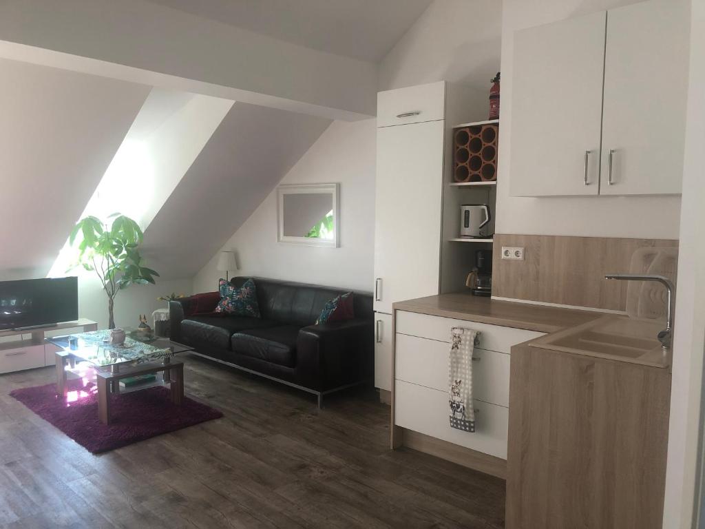 uma sala de estar com um sofá preto e uma cozinha em Old Bridge View Apartment em Heidelberg