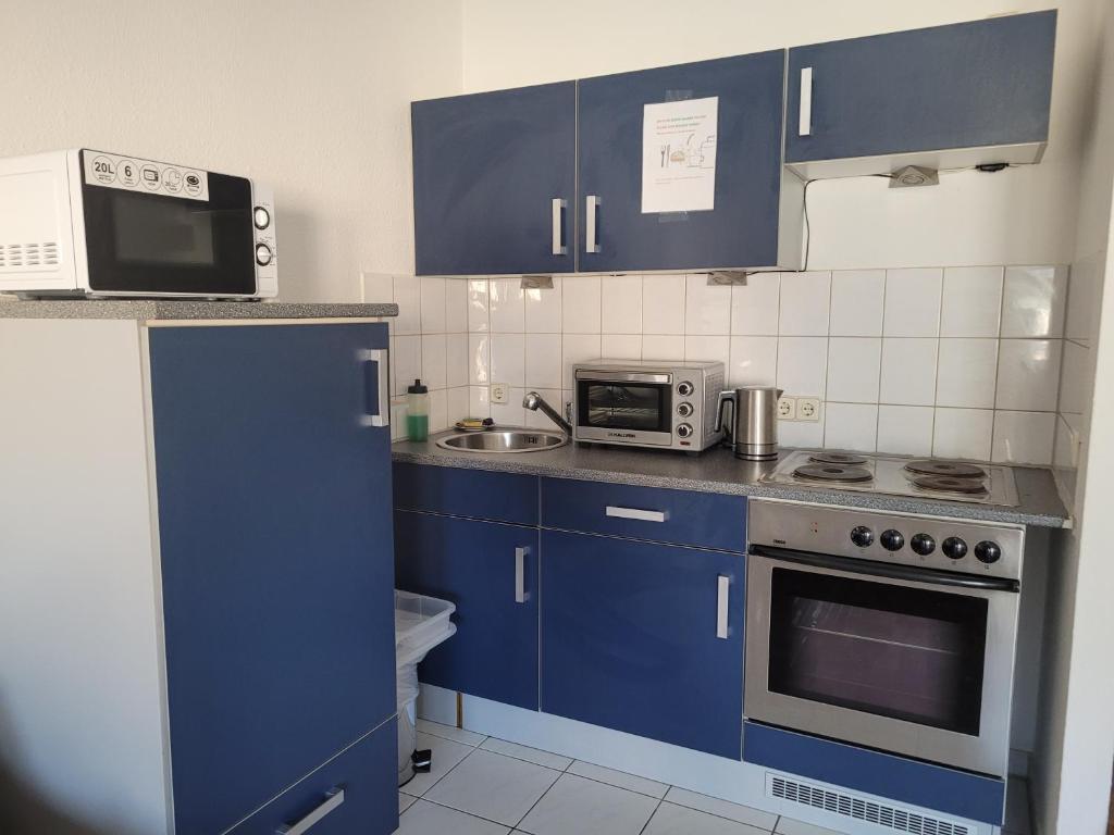 eine Küche mit blauen Schränken und einer Mikrowelle in der Unterkunft Mickten Hertz in Dresden