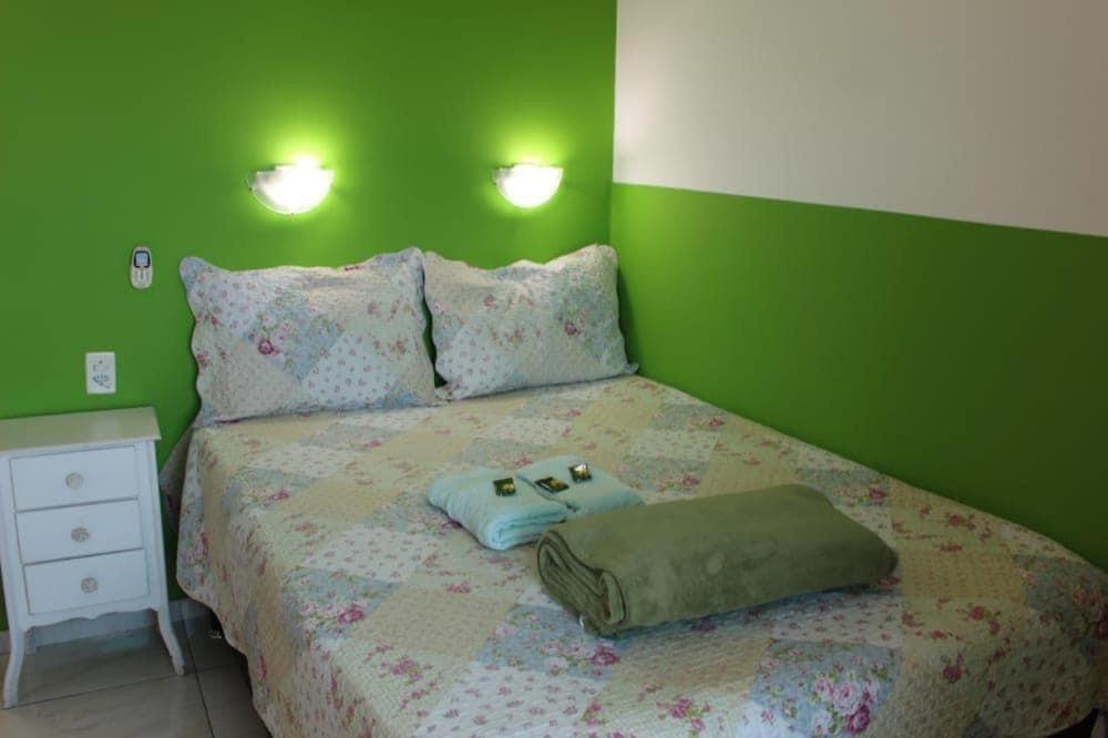 a green bedroom with a bed with two bags on it at pousada do rei in Pedra de Guaratiba