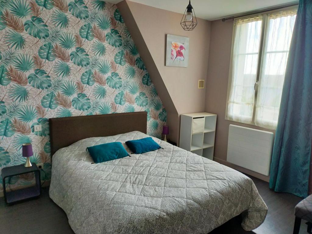 a bedroom with a bed with blue pillows on it at Les Chambres du Faubourg in Montrichard