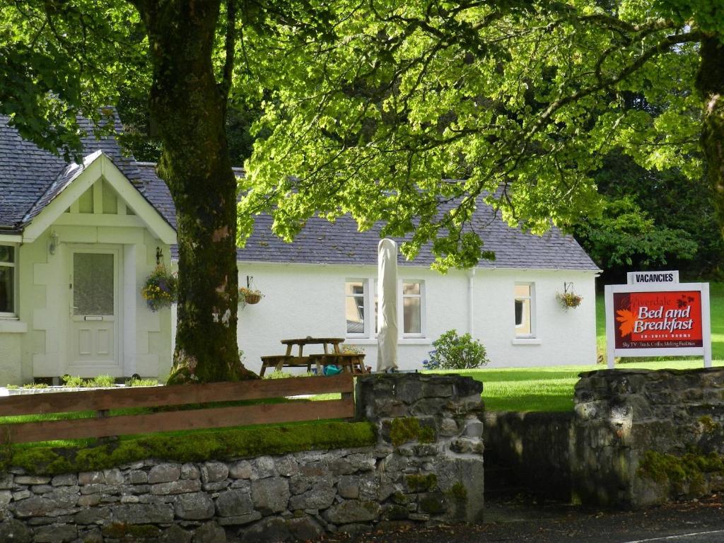 a white house with a tree and a bench at Bonnie Lodge by Broadford Hotel in Broadford