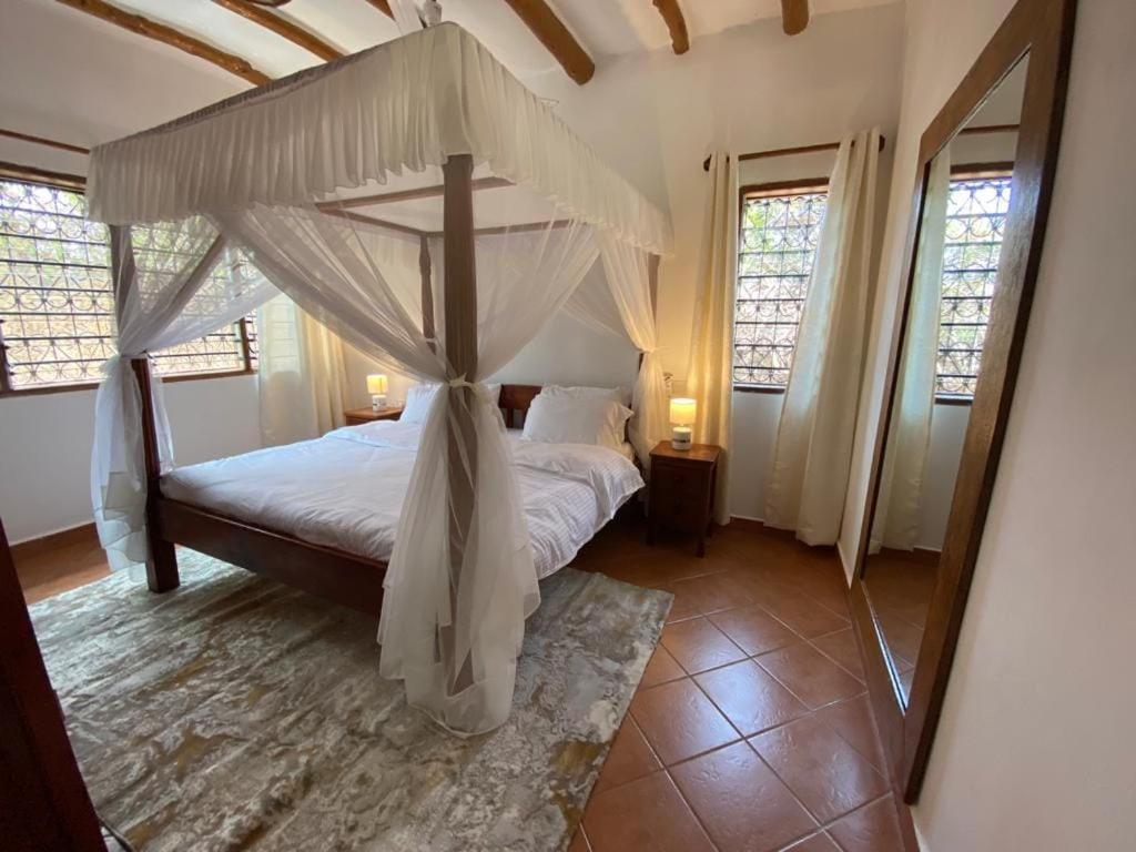 - une chambre avec un lit à baldaquin dans l'établissement Villa Isla del Amore, à Watamu