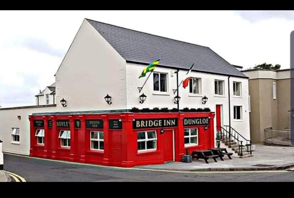 een rood-wit gebouw met een grote herberg bij Bridge Inn Studio Apartments in Donegal