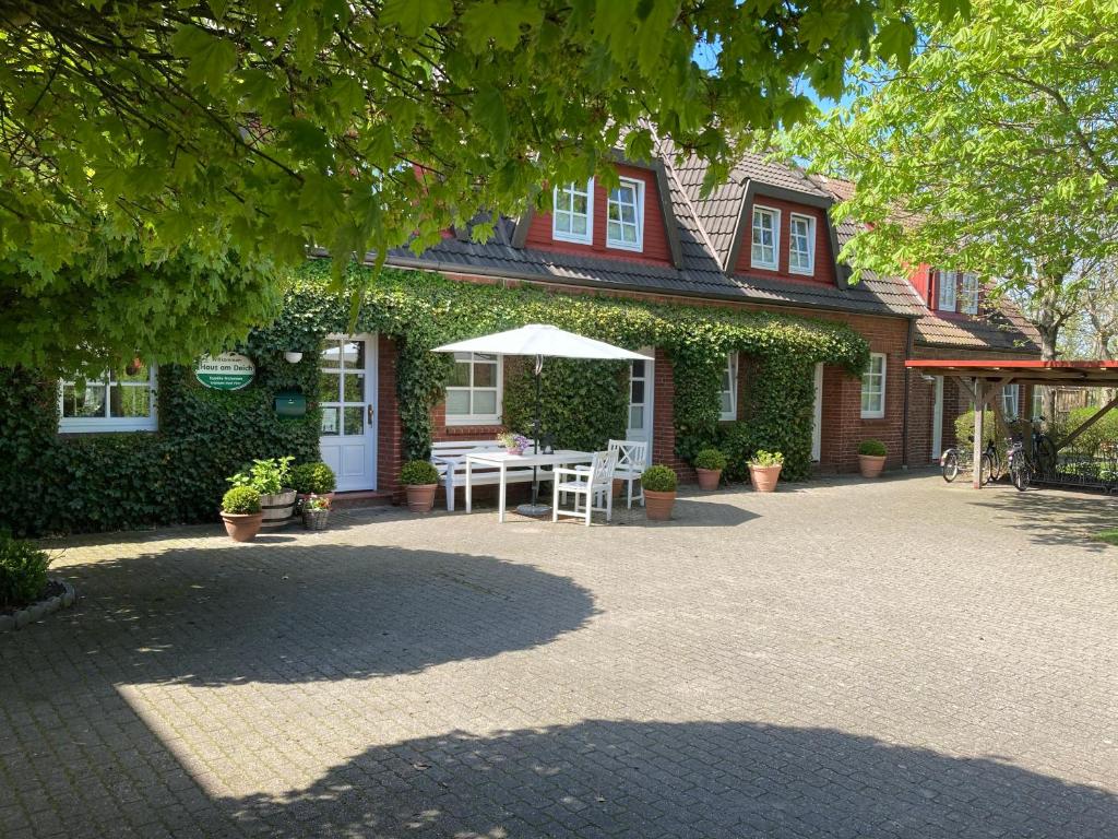 uma casa com um pátio com uma mesa e um guarda-chuva em Haus am Deich em Utersum