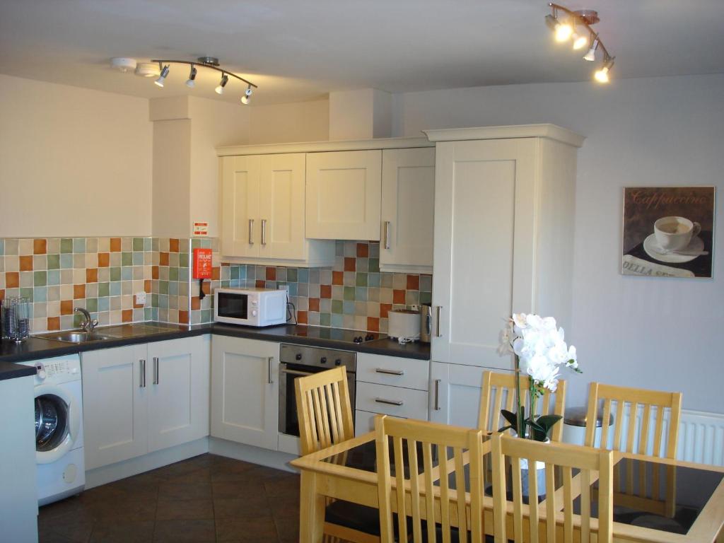 a kitchen with white cabinets and a table and chairs at Apt 7A Waterfoot Apartment in Newcastle