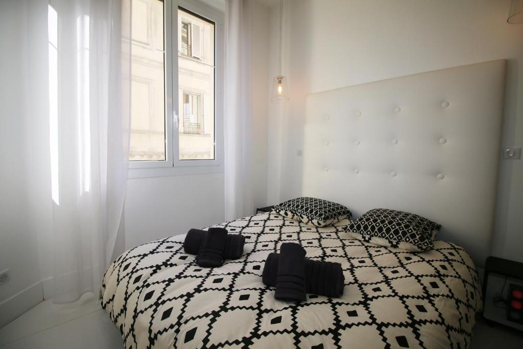 a bedroom with a bed with black and white sheets and a window at High-End Apartment, Hyper Center, Near The Beaches in Nice