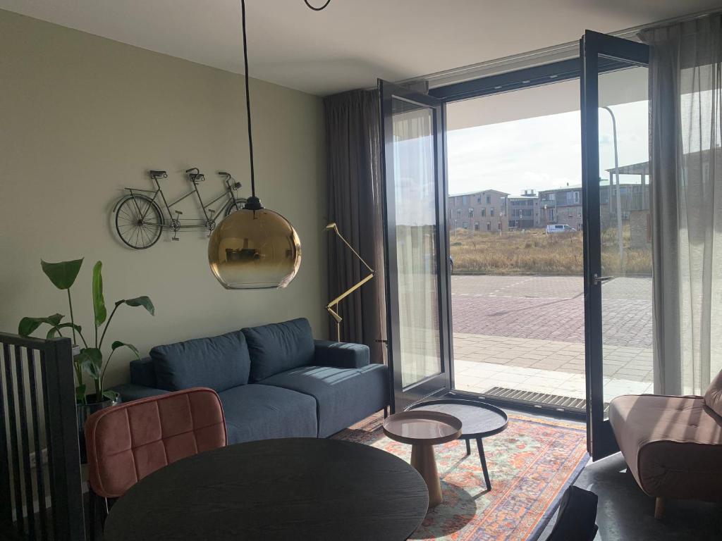 a living room with a blue couch and a bike on the wall at Strand & meer in Katwijk