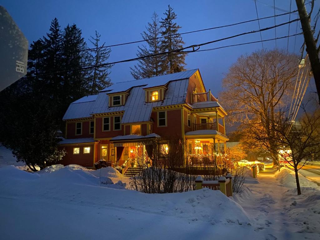 a large house in the snow at night at The Village Inn of Woodstock in Woodstock