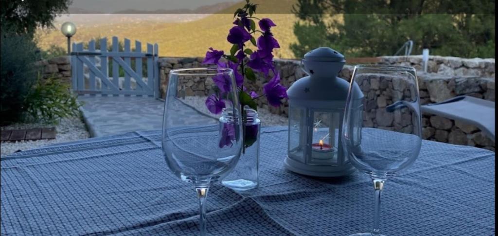 una mesa con dos copas de vino y un exprimidor con flores púrpuras en Appartamento Giada 3, en Sole Ruiu