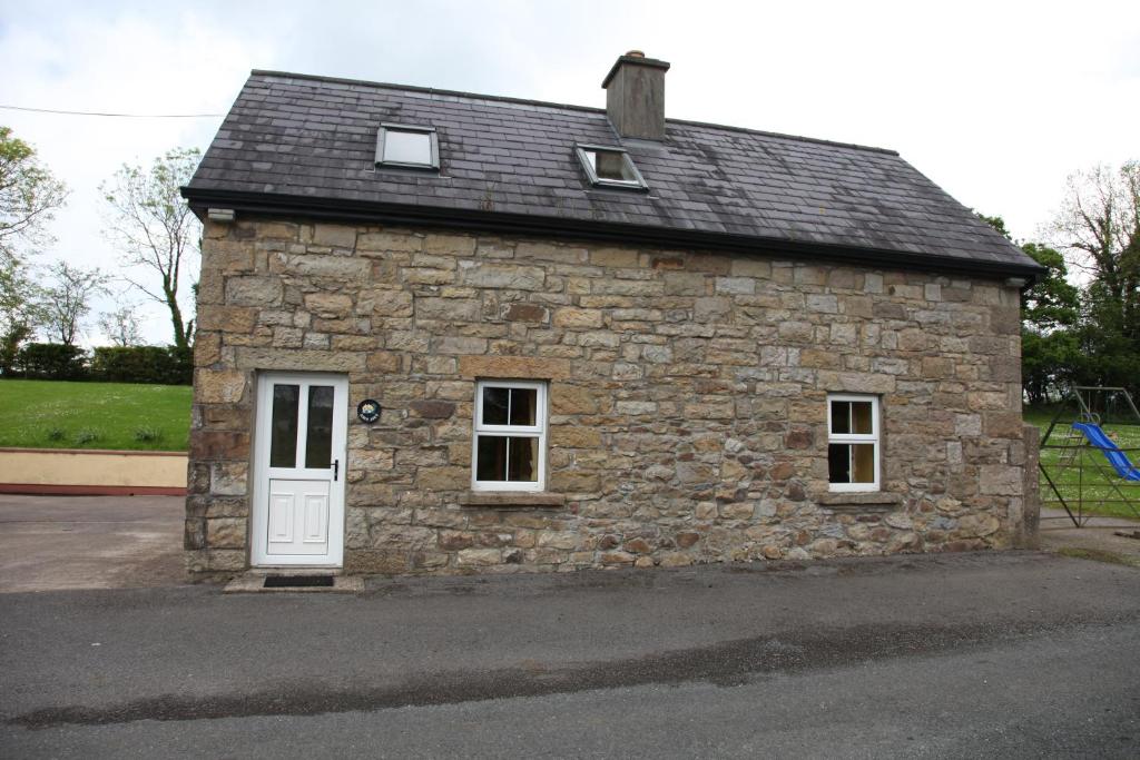 um pequeno edifício de pedra com uma porta branca em John Joe's Self Catering em Blacklion