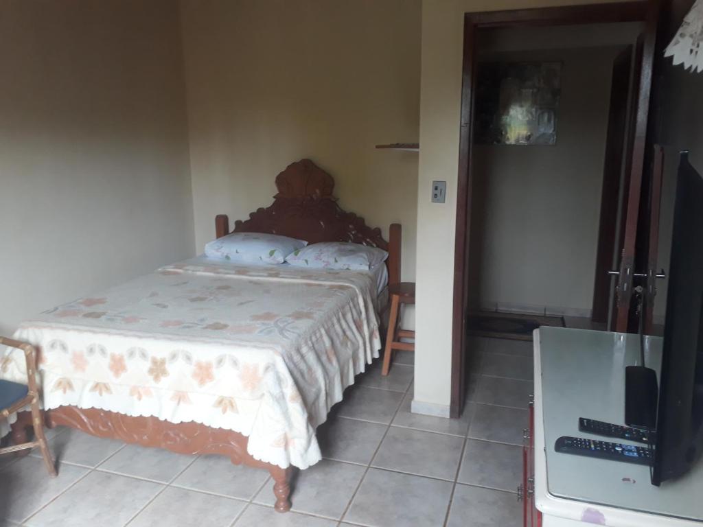 um quarto com uma cama e uma televisão num quarto em Casa das Flores em Chapada dos Guimarães