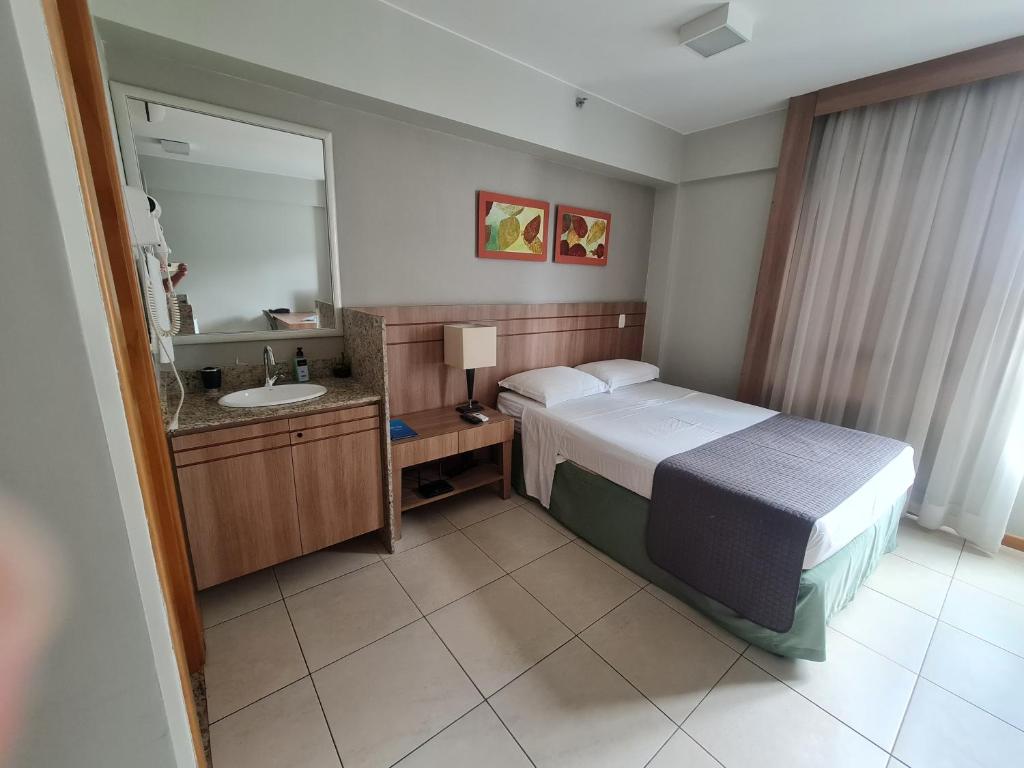 a hotel room with a bed and a sink at BSB FLAT - MELHOR LOCALIZAÇÃO in Brasilia