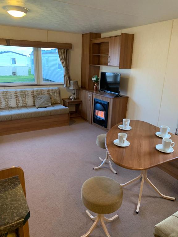 uma sala de estar com uma mesa e cadeiras e uma lareira em Cosy Private Caravan Romney Sands Holiday Park em New Romney