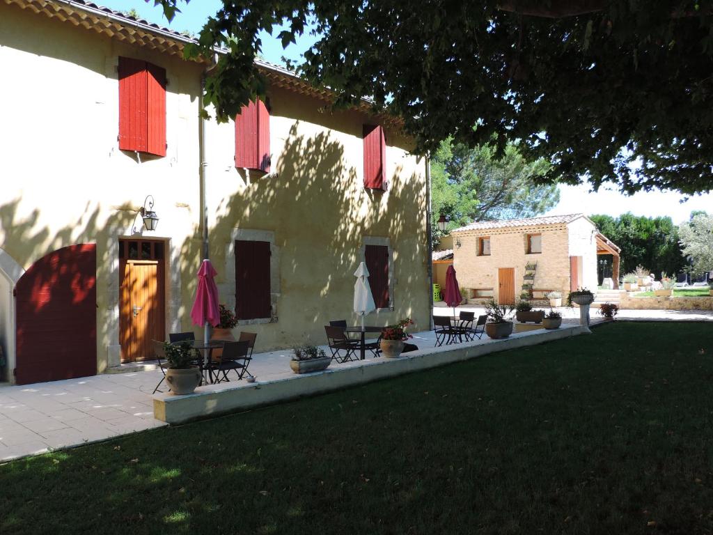 un bâtiment avec des tables et des chaises dans une cour dans l'établissement Mas de la Sauline, à La Roque-dʼAnthéron