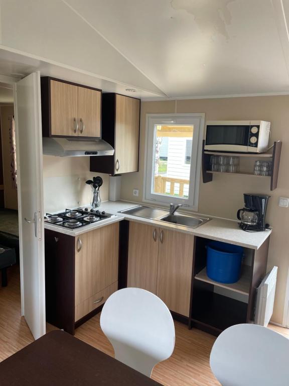 une petite cuisine avec une cuisinière et un micro-ondes dans l'établissement Mobilhome 6 personnes, à Saint-Georges-de-Didonne