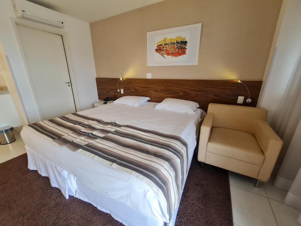 um quarto com uma cama grande e uma cadeira em Flat Particular - SHN - Vista Livre Esplanada em Brasília