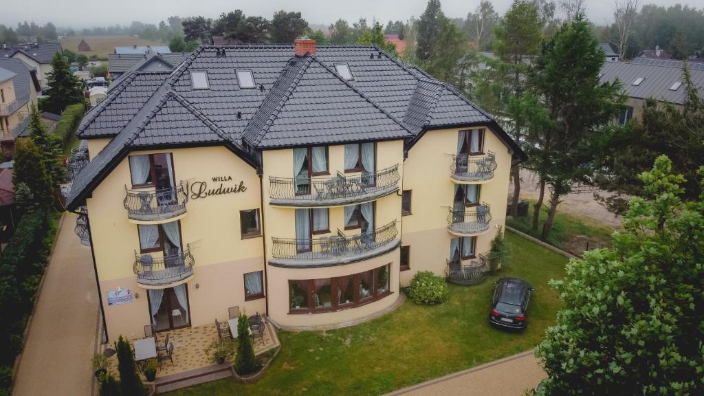 une grande maison jaune avec un toit noir dans l'établissement Willa Ludwik SPA & Wellness, à Dębki