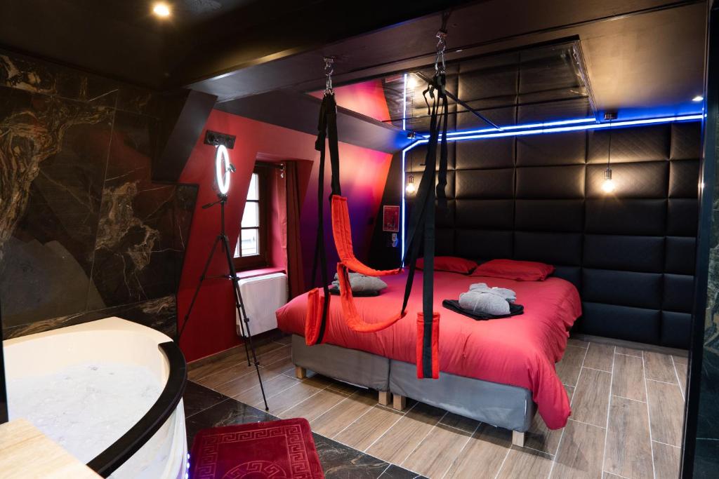 a bedroom with a red bed with a blue light at Capsule Secret - Jacuzzi - Netflix &amp; Home cinéma - Jeux de couple - Barre de pole dance in Valenciennes