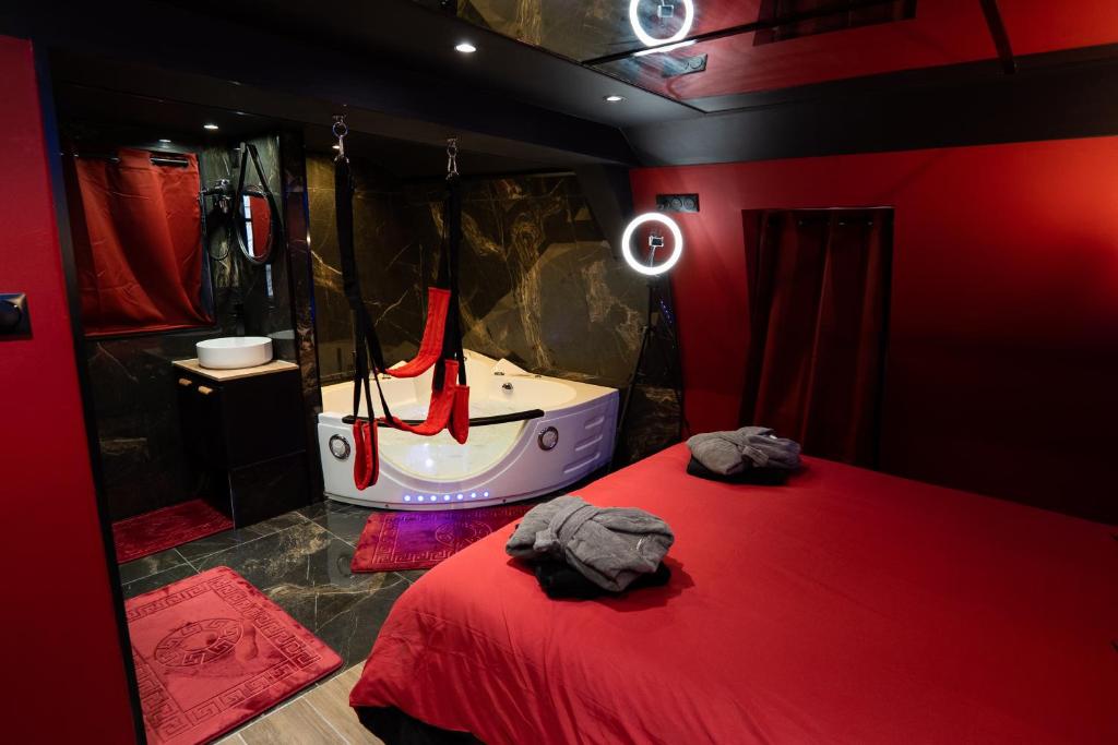 a room with a bed and a bathroom with a tub at Capsule Secret - Jacuzzi - Netflix &amp; Home cinéma - Jeux de couple - Barre de pole dance in Valenciennes
