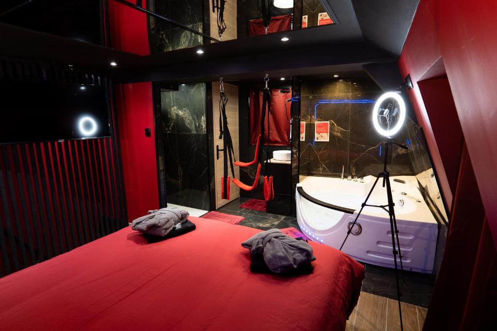 a room with a red bed and a bath tub at Capsule Secret - Jacuzzi - Netflix &amp; Home cinéma - Jeux de couple - Barre de pole dance in Valenciennes