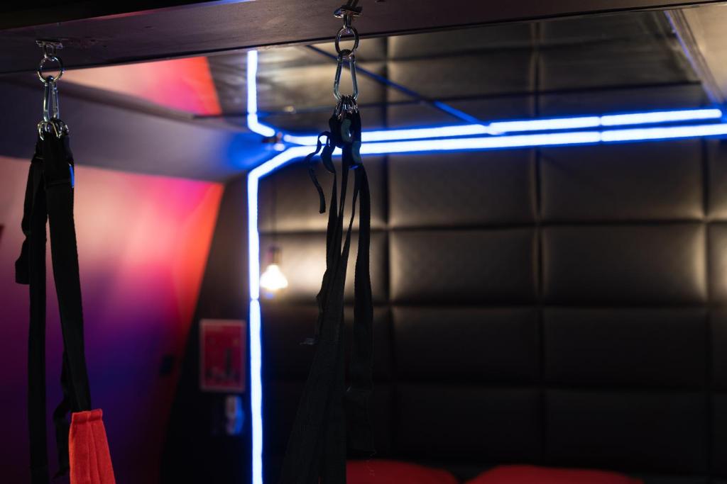 a dark room with a curtain and a neon light at Capsule Secret - Jacuzzi - Netflix &amp; Home cinéma - Jeux de couple - Barre de pole dance in Valenciennes