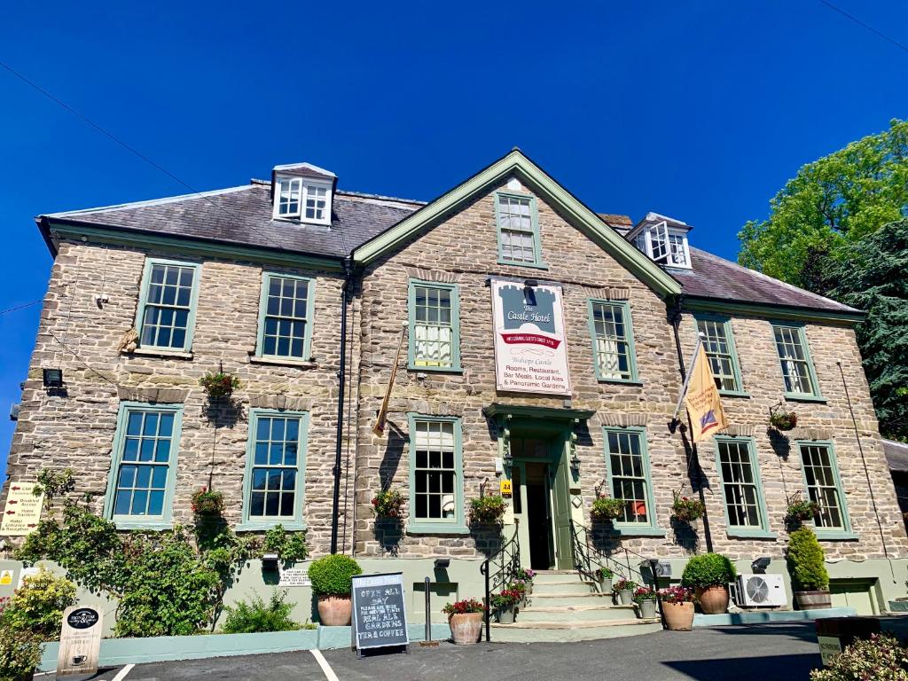 een oud stenen gebouw met een bord erop bij The Castle Hotel in Bishops Castle