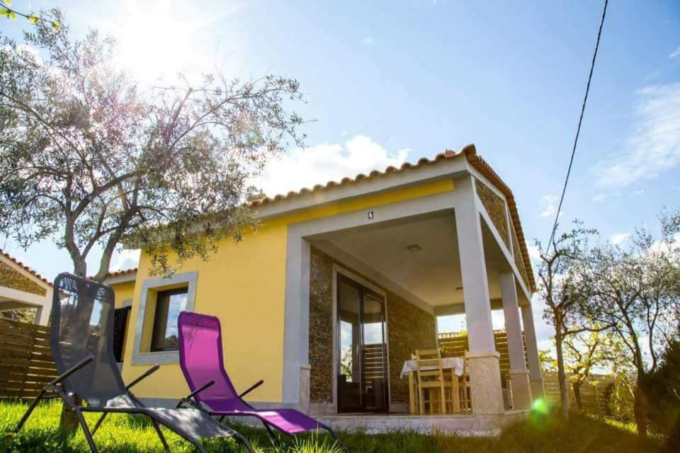 deux chaises violettes devant une maison jaune dans l'établissement Casas do Paço - Casas de Férias, à Cabeceiras de Basto