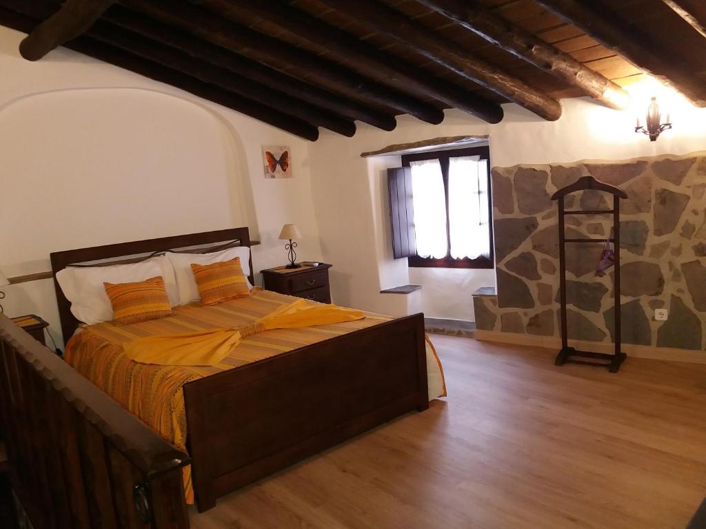 a bedroom with a bed with orange sheets and a window at Casa Daterra in Monsaraz