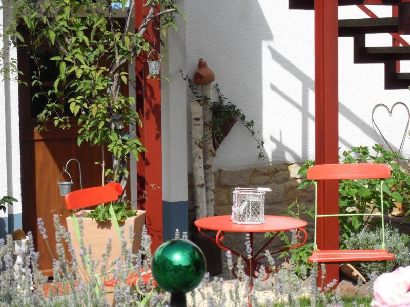 a red table and two chairs in a garden at Loblocher Max und Moritz in Neustadt an der Weinstraße