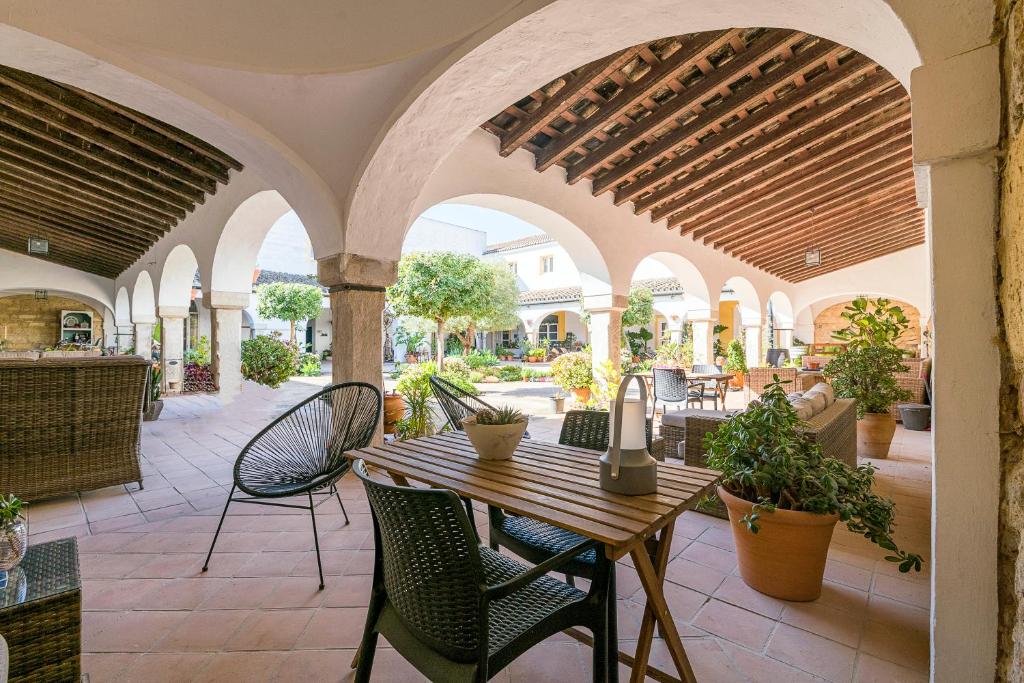 een patio met een houten tafel en stoelen bij Cream Loft. Siente Jerez. Parking+Wifi+Netflix in Jerez de la Frontera