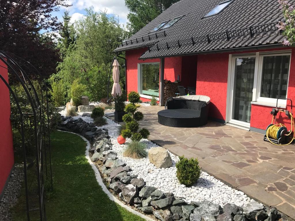 un cortile con un giardino roccioso e una casa rossa di Tolle Ferienwohnung mit Loggia in Schauenstein 100qm bei Hof an der Saale Frankenwald a Schauenstein