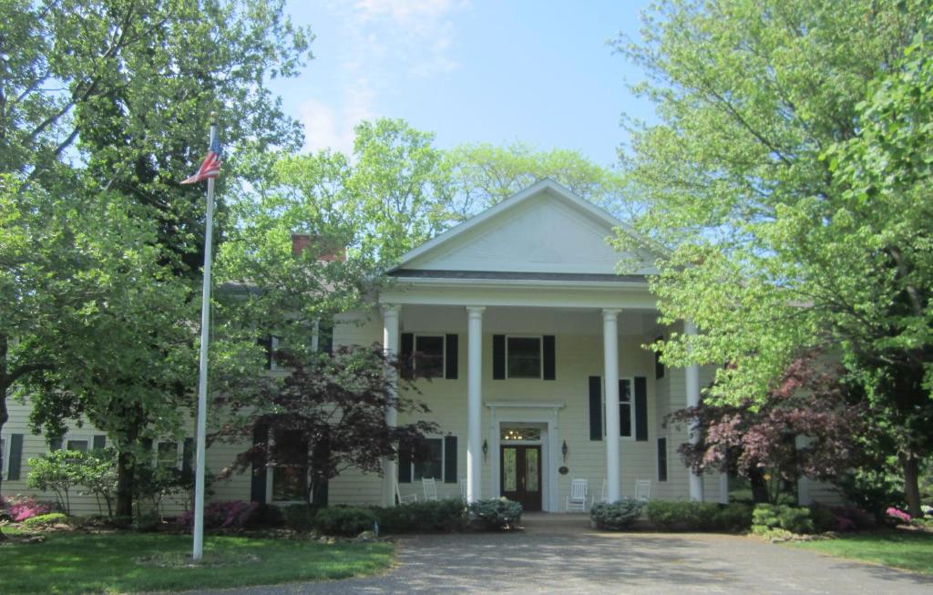 une maison blanche dotée d'un drapeau américain devant elle dans l'établissement Farrell House Lodge at Sunnybrook Trout Club, à Sandusky