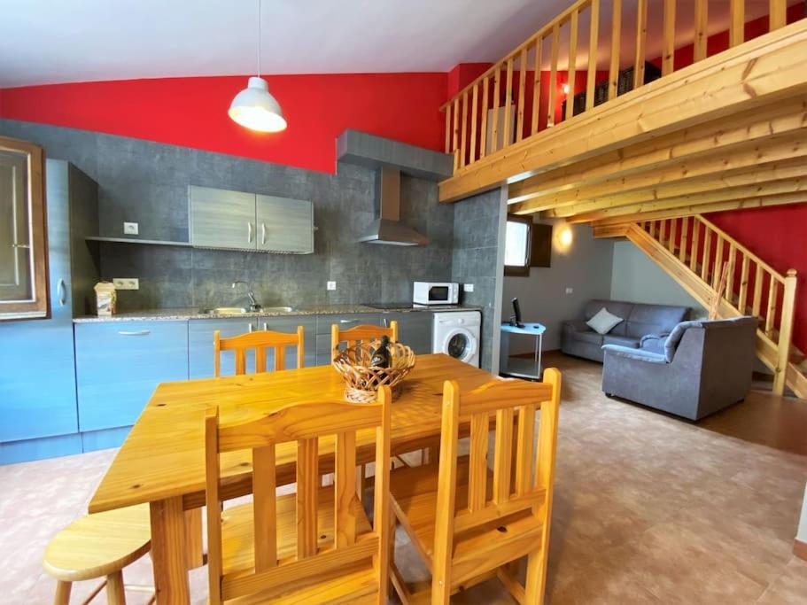 una cucina e una sala da pranzo con tavolo e sedie in legno di La Vall Apartaments Dúplex a Sant Llorenç de Morunys