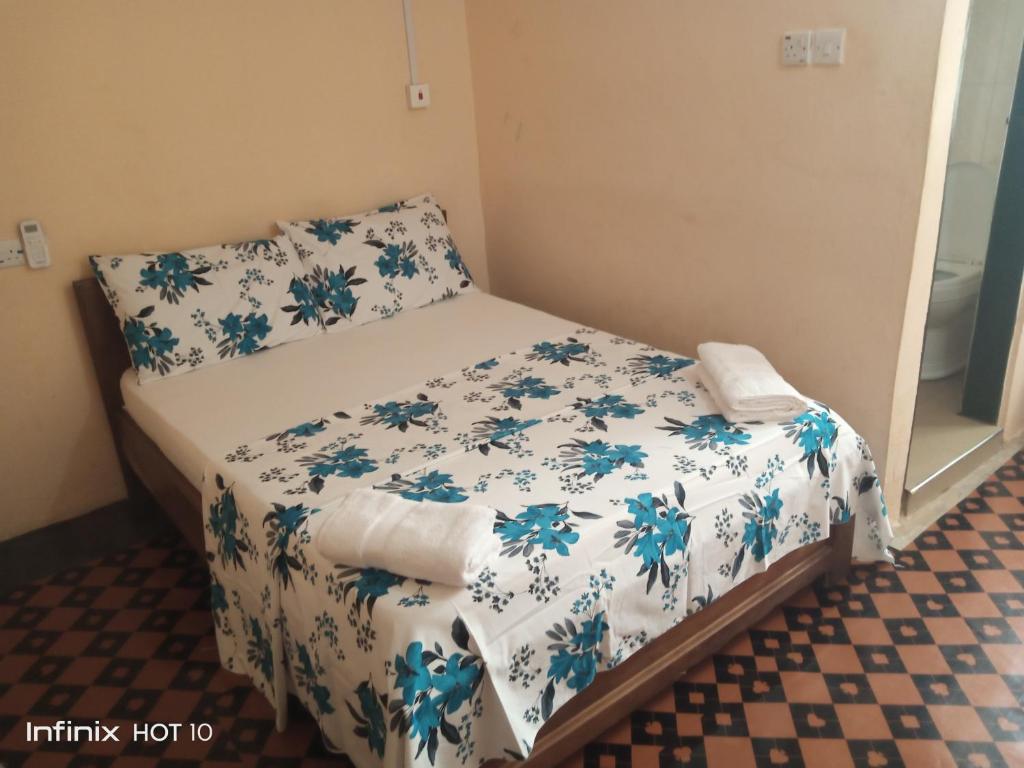a small bedroom with a bed with blue flowers at Wli Waterfalls Inn in Wli Afegame