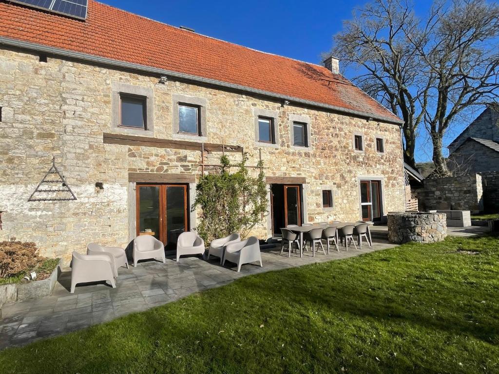 un bâtiment avec des chaises et des tables devant lui dans l'établissement Le gîte d’Hayen, à Sprimont