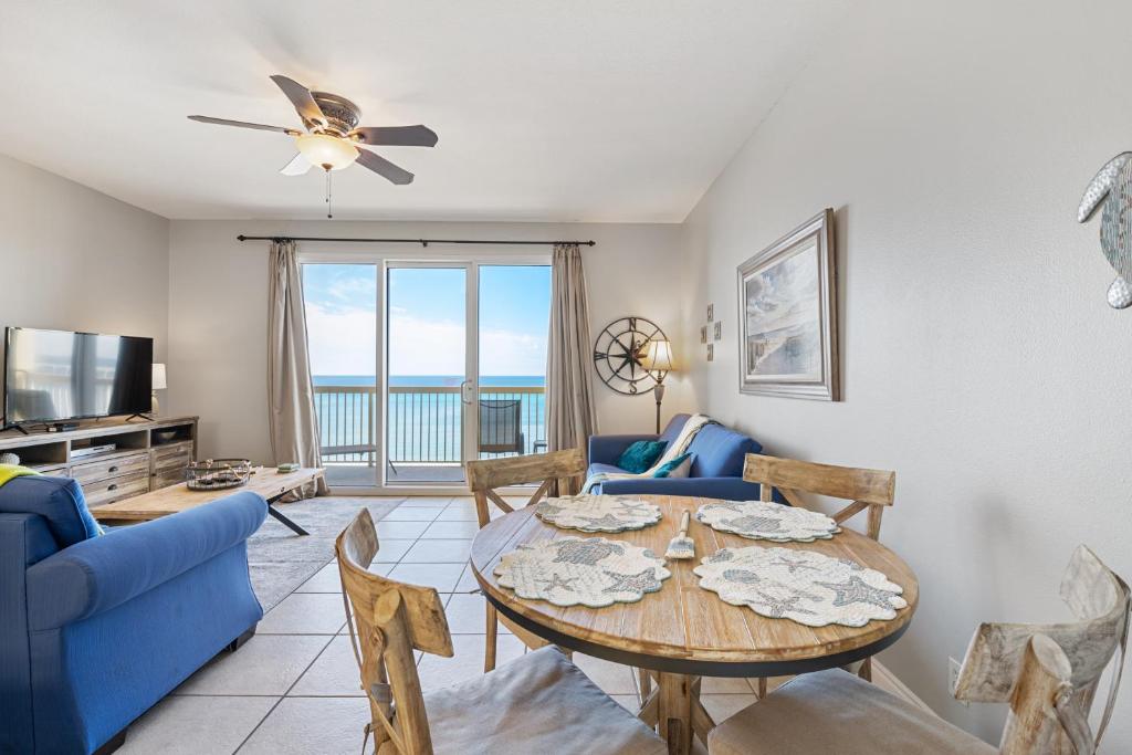 sala de estar con mesa, sillas y TV en Calypso Resort Beachfront Condo, en Panama City Beach