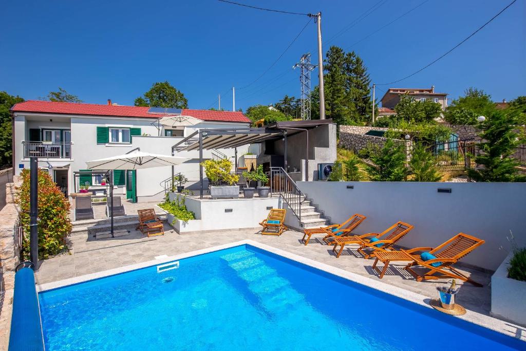 a swimming pool with chairs and a house at Villa Rhapsody in Hreljin