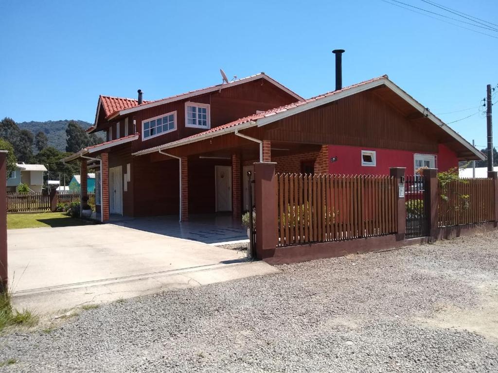 a red house with a fence in front of it at Rosa dos Ventos - CASA in Urubici