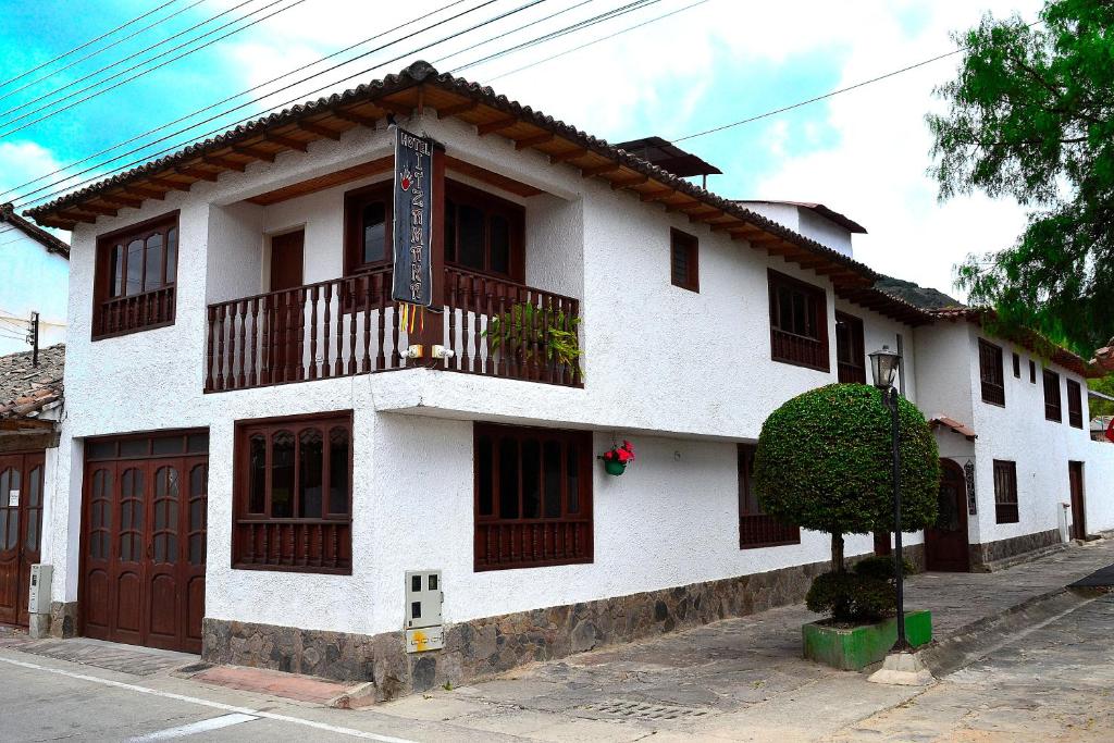 a white building with a balcony on a street at Hotel Itzamana in Iza